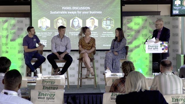 Panelists are seated on stools discussing "Sustainable swaps for your business" at the Energy Well Spent Summit. The host stands at a podium, and the audience is seated facing the stage.